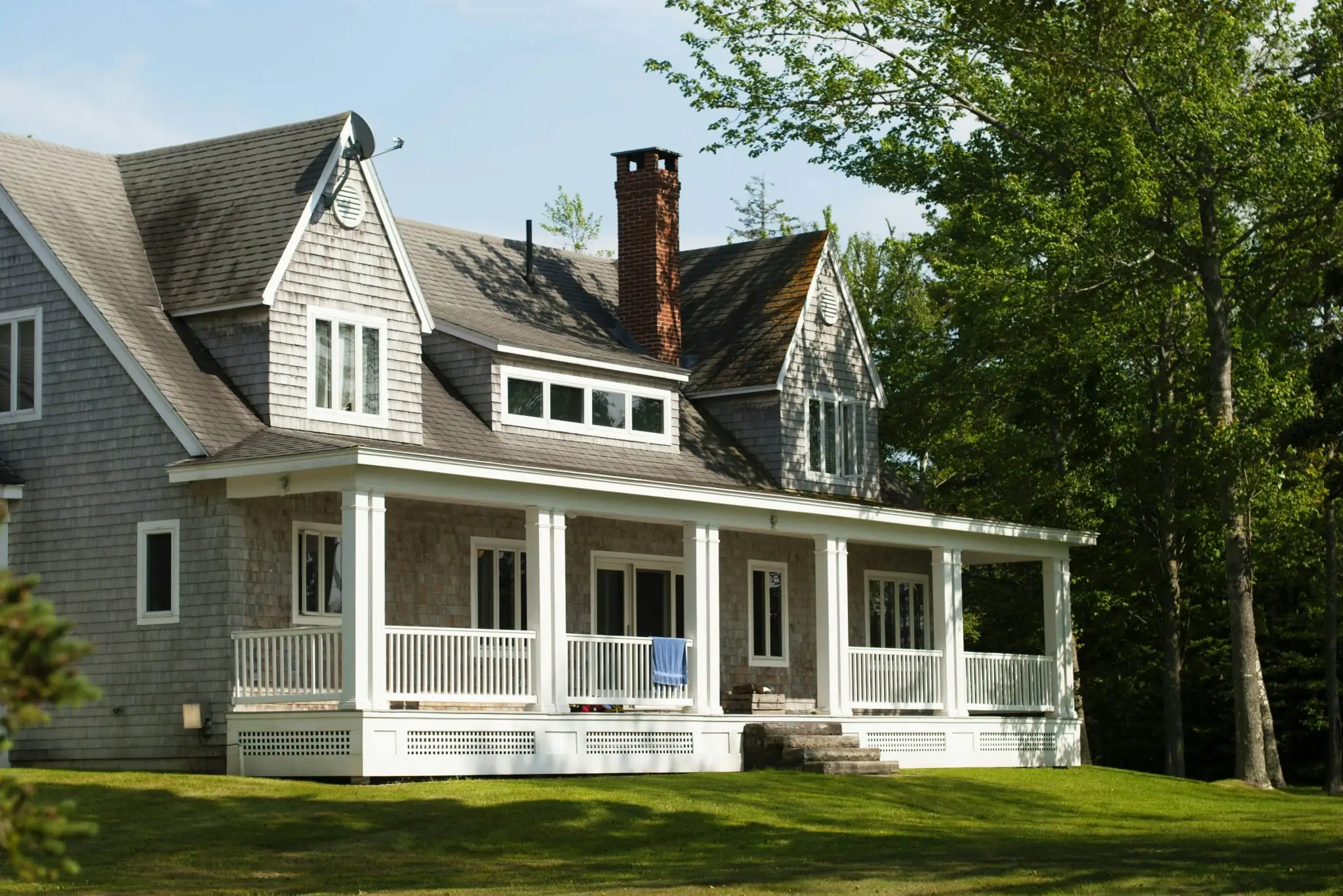 Large house with shingled roof showing dark streaks and moss growth — image for "Storm Damage vs. Wear and Tear".