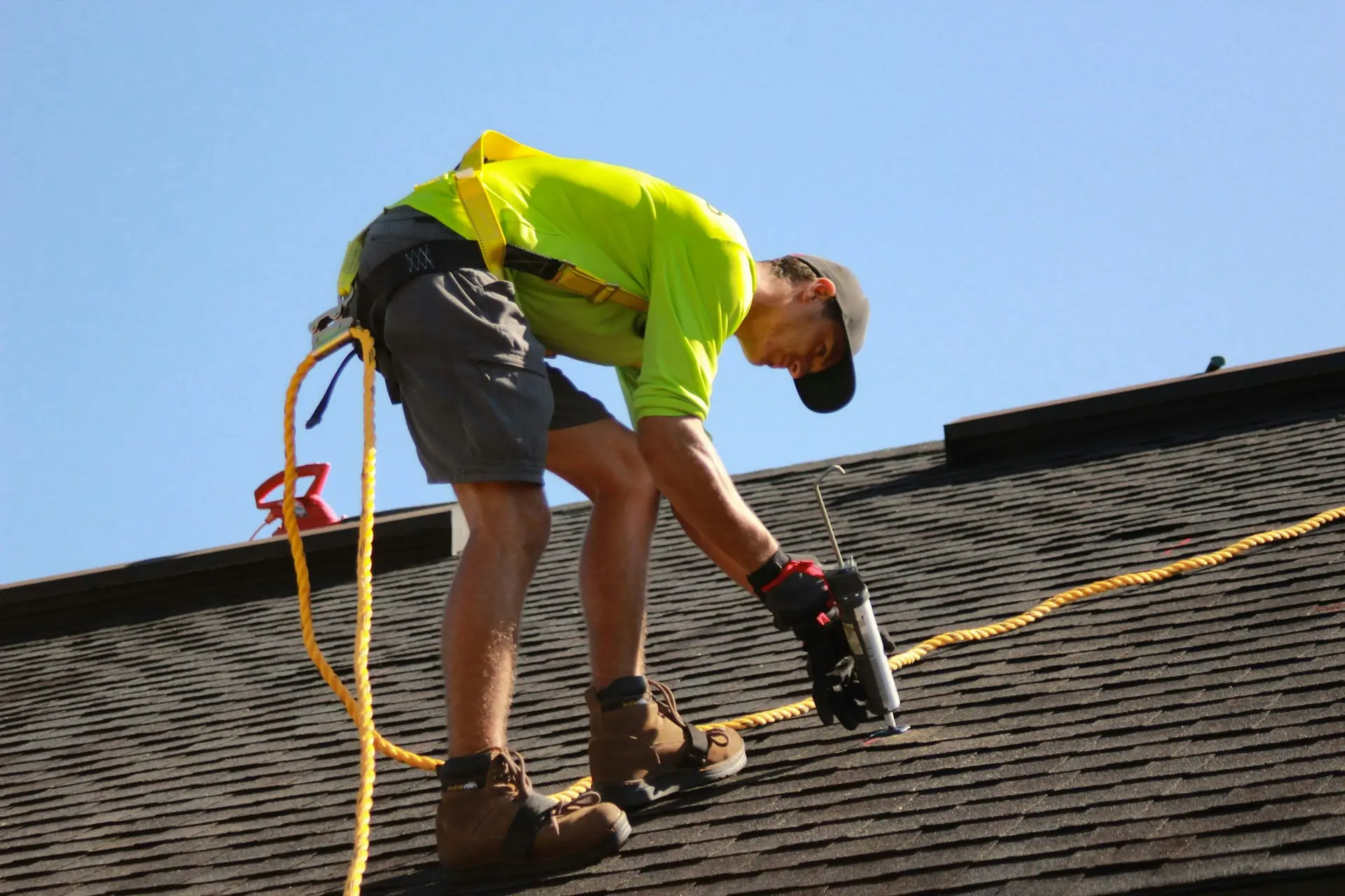 Detailed view of a roofing professional applying sealant during a roof inspection to determine if repairs are needed for storm damage vs. wear and tear.