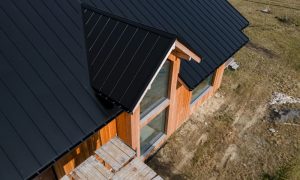 Aerial view of a modern wooden house with a black metal roof.