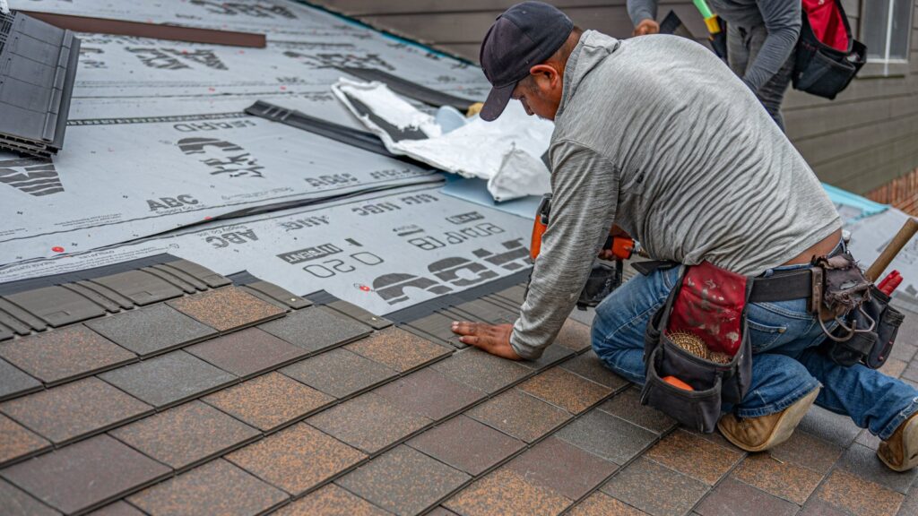 Skilled roofer installing asphalt shingles, ensuring quality home renovation
