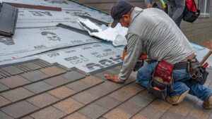 Skilled roofer installing asphalt shingles, ensuring quality home renovation